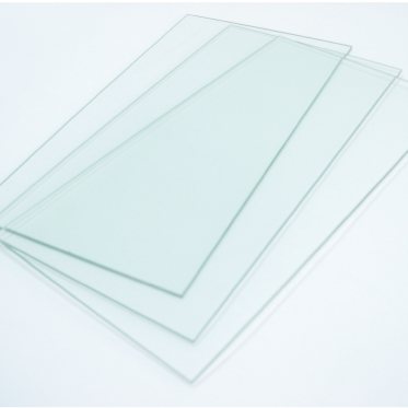 Stack of thin rectangular glass sheets on a white surface