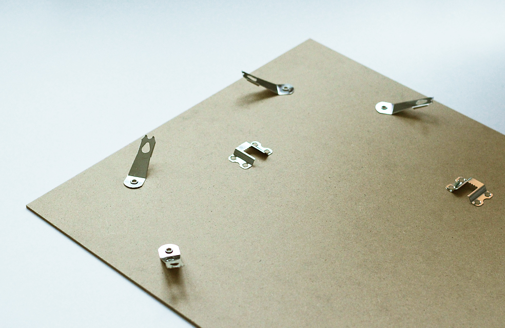 Back of a picture frame with metal hanging hardware and clips