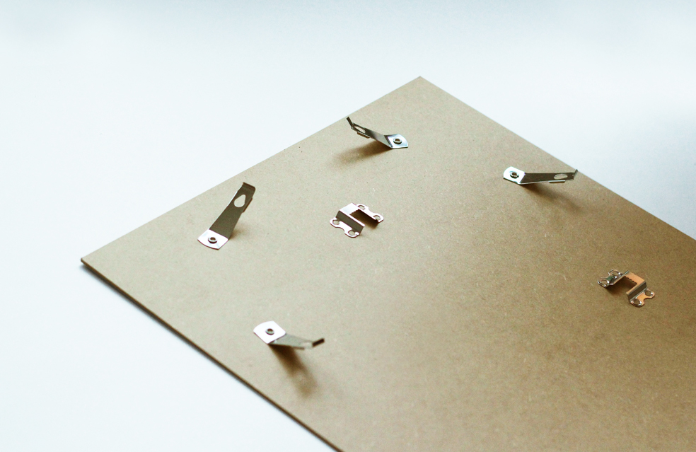 Back of a picture frame with metal hanging clips and sawtooth hangers